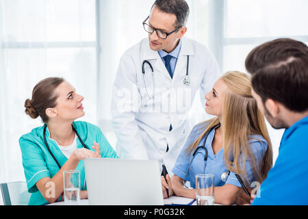 Team aus Ärzten und Hausarzt in Gespräch und mit Laptop Stockfoto