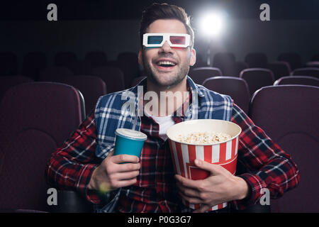 Aufgeregt Mann in der 3D-Brille mit Popcorn und Soda beobachten Film im Kino. Stockfoto