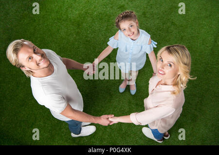 Glückliche Familie mit Blick auf die Kamera beim stehen im Kreis und halten sich an den Händen Stockfoto