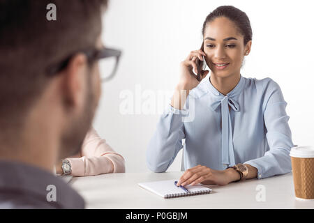 Junge Geschäftsfrau auf Smartphone, während man bei der Sitzung warten Stockfoto