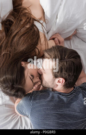 Draufsicht auf das junge Paar Küssen im Bett am Morgen Stockfoto