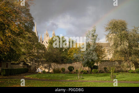 Peterborough Kathedrale gesehen von Süden über Bischof Gärten. Gut beleuchtet mit Regenbogen und dunkle Wolken bei einem kurzen Gewitter Stockfoto