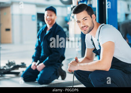 Junge automechanics Sitzen auf einem Stock einer Reparaturwerkstatt. Stockfoto