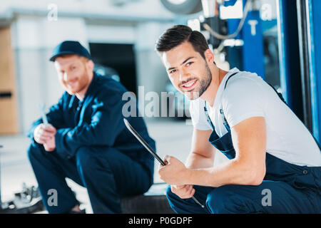 Junge automechanics Sitzen auf einem Stock einer Reparaturwerkstatt. Stockfoto