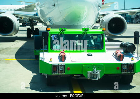 Großes Flugzeug von Flughafen Schlepper Traktor Besteuerung am Flugplatz in Docking Position für Fluggastbrücken das Flugzeug gezogen Stockfoto