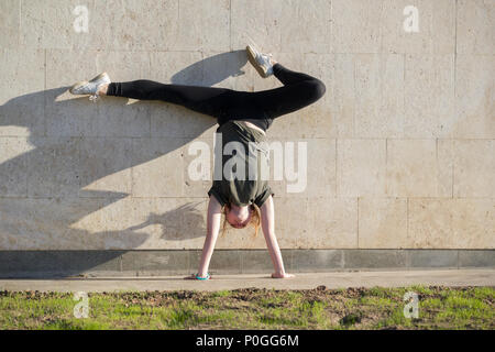 Junge weibliche handstand an der Wand führt akrobatische Elemente Stockfoto