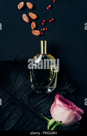 Blick von oben auf die Flasche Parfüm mit rose bud und Gewürzen auf Schwarz Stockfoto