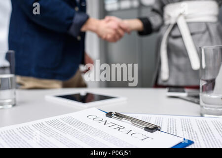 Geschäftspartner Händeschütteln mit Vertrag auf dem Tisch zu neuen Kenntnissen und Schutzrechten Stockfoto