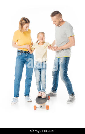 Lächelnd Familie halten sich an den Händen der kleinen Tochter auf Skateboard isoliert auf weißem Stockfoto