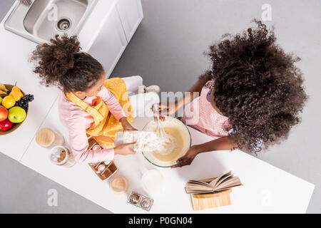 Ansicht von oben der afrikanischen amerikanischen Mutter und Curly Tochter, Teig in der Schüssel auf Küche Stockfoto