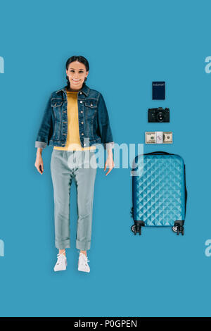 Blick von oben auf die stilvolle Frau mit Koffer, Geld, Foto, Kamera und Pass auf blauem Hintergrund isoliert Stockfoto