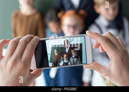 Nahaufnahme der jungen Lehrerin und niedlichen kleinen Studenten fotografieren mit Smartphone Stockfoto