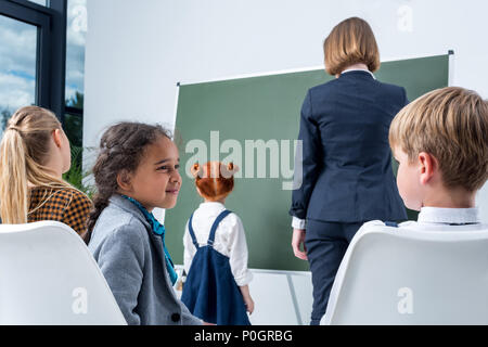 Junge weibliche Lehrer mit wenig Schüler an Tafel und erklären Lektion Stockfoto