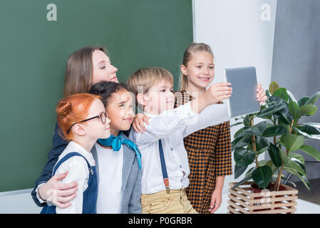 Junge Lehrerin mit niedlichen kleinen Studenten selfie mit digitalen Tablet in der Klasse Stockfoto