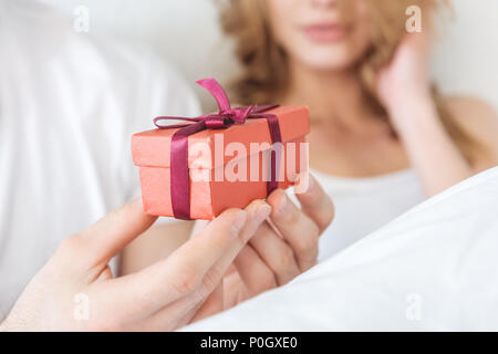 7/8-Ansicht von Mann mit roter Geschenkbox zu seiner Freundin Stockfoto