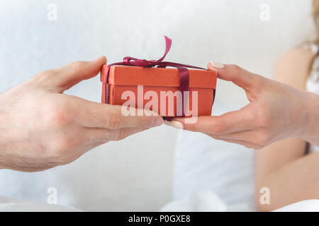 7/8-Ansicht von Mann mit roter Geschenkbox zu seiner Freundin Stockfoto