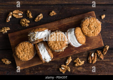 Eis-Sandwiches mit Muttern und Vollkorn Cookies. Hausgemachtes Vanilleeis Sandwiches auf dunklem Hintergrund. Stockfoto