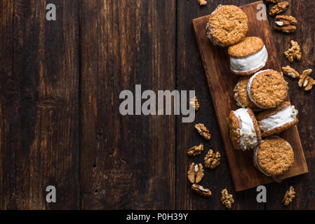 Eis-Sandwiches mit Muttern und Vollkorn Cookies. Hausgemachtes Vanilleeis Sandwiches auf dunklem Hintergrund. Stockfoto