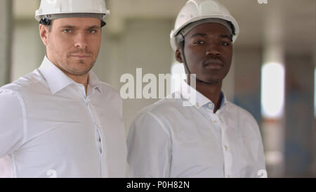 Zwei Unternehmer an der Kamera in Baustelle suchen Stockfoto