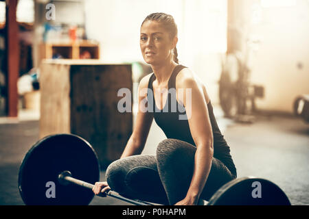 Schwerpunkt junge Frau in Sportkleidung Vorbereitung Gewichte beim Training Session in der Turnhalle zu heben Stockfoto
