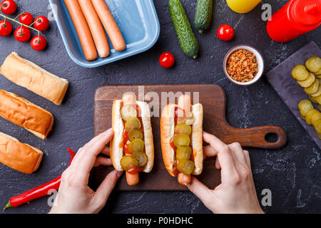 Foto von oben der Mann tun Hotdogs auf Schneidebrett auf Tabelle mit Würstchen Stockfoto