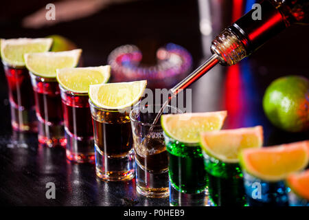 Barkeeper gießen alkoholisches Getränk in kleine Gläser an der Bar. Farbenfrohe Cocktails an der Bar. Farbenfrohe Aufnahmen im Club. Alkoholische Getränk in verschiedenen c Stockfoto