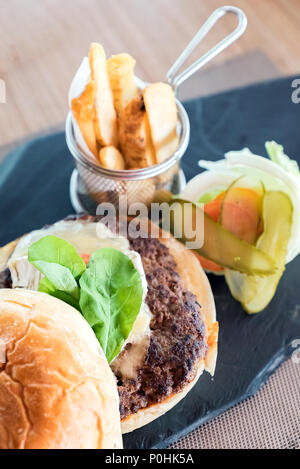 Hausgemachte überlast Rindfleisch Hamburger mit frischem Gemüse und Käse mit Pommes Stockfoto
