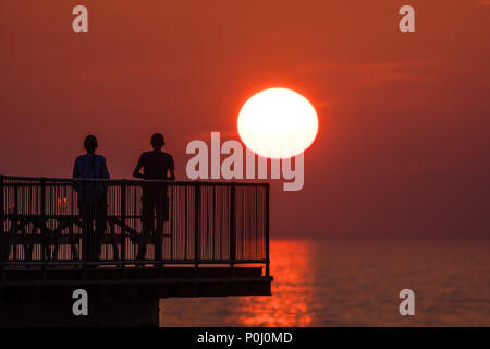 Aberystwyth Wales UK, Samstag, 09. Juni 2018 Deutschland Wetter: Die herrliche Sonne im orange sky Silhouetten Menschen genießen Sie einen Drink auf der viktorianischen Badeort Pier in Aberystwyth an der Westküste von Wales, am Ende eines Tages des heißen Sommer Sonnenschein Foto © Keith Morris/Alamy leben Nachrichten Stockfoto