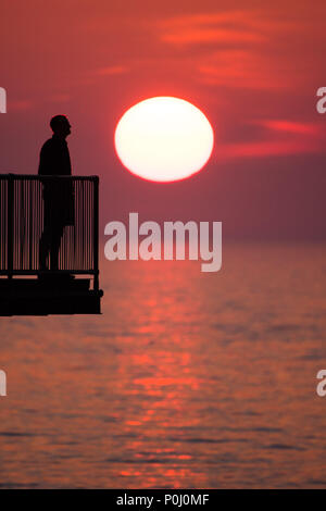 Aberystwyth Wales UK, Samstag, 09. Juni 2018 Deutschland Wetter: Die herrliche Sonne im orange sky Silhouetten Menschen genießen Sie einen Drink auf der viktorianischen Badeort Pier in Aberystwyth an der Westküste von Wales, am Ende eines Tages des heißen Sommer Sonnenschein Foto © Keith Morris/Alamy leben Nachrichten Stockfoto