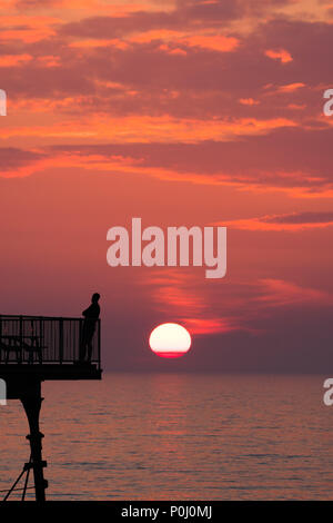 Aberystwyth Wales UK, Samstag, 09. Juni 2018 Deutschland Wetter: Die herrliche Sonne im orange sky Silhouetten Menschen genießen Sie einen Drink auf der viktorianischen Badeort Pier in Aberystwyth an der Westküste von Wales, am Ende eines Tages des heißen Sommer Sonnenschein Foto © Keith Morris/Alamy leben Nachrichten Stockfoto