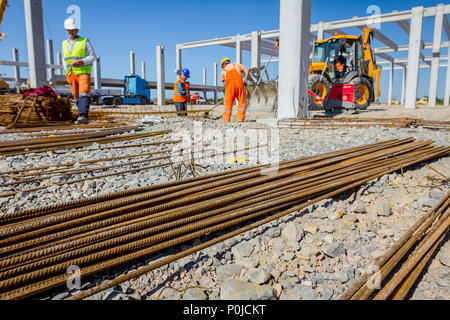 Blick auf gestapelte rostige Stahlarmierung für Beton, Baustelle ist im Hintergrund. Stockfoto