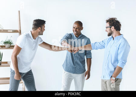Multiethnische Gruppe der jungen Unternehmer halten sich an den Händen zusammen Stockfoto