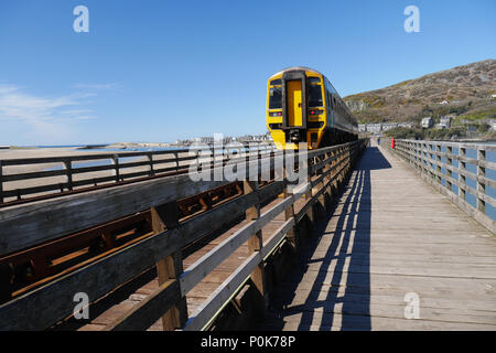 Afon mawddach - Tywyn, Wales, UK. Mann auf dem Zug an der Mündung der Bahn/Fuß-Brücke. Stockfoto