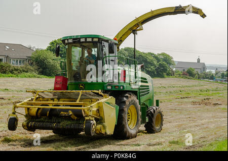 John Deere 7500 Mäher sammelt auf einem Bauernhof in Schull, County Cork, Irland, geschnittenes Gras für Silage. Stockfoto