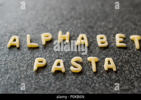 Raw Alphabet Nudeln mit Buchstaben auf Granit grau Oberfläche geschrieben. Ungekocht Bio-lebensmittel. Stockfoto