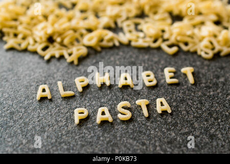 Raw Alphabet Nudeln mit Buchstaben auf Granit grau Oberfläche geschrieben. Ungekocht Bio-lebensmittel. Stockfoto