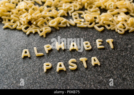 Raw Alphabet Nudeln mit Buchstaben auf Granit grau Oberfläche geschrieben. Ungekocht Bio-lebensmittel. Stockfoto