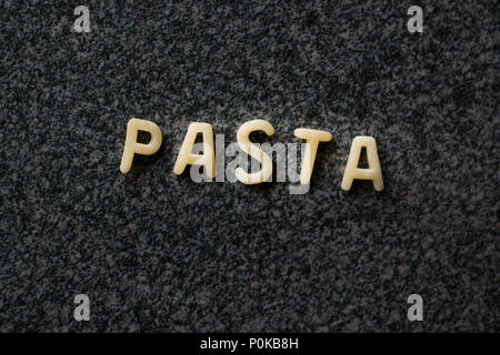Raw Alphabet Nudeln mit Buchstaben auf Granit grau Oberfläche geschrieben. Ungekocht Bio-lebensmittel. Stockfoto