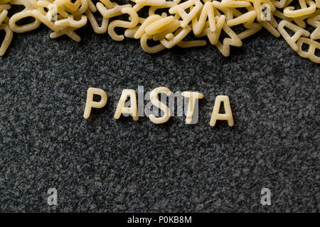Raw Alphabet Nudeln mit Buchstaben auf Granit grau Oberfläche geschrieben. Ungekocht Bio-lebensmittel. Stockfoto