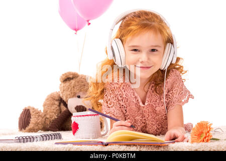 Lächelnd rote Haare Kind in Kopfhörer bei Kamera isoliert auf weißem suchen Stockfoto