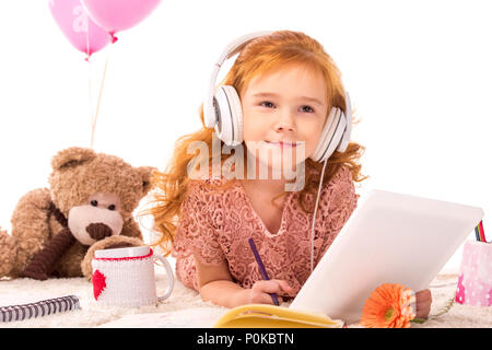 Rote Haare Zicklein liegend auf Teppich und Musik hören isoliert auf weißem Stockfoto