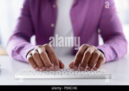 Zugeschnittenes Bild der afrikanischen amerikanischen Mann mit der Eingabe von der Tastatur Stockfoto