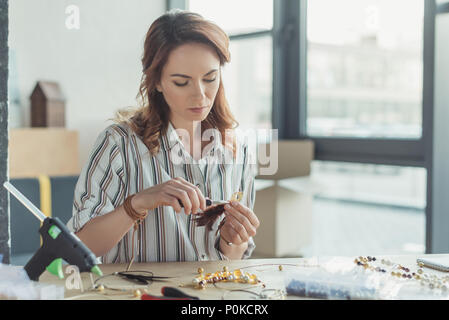 Konzentrierte junge Frau, Zubehör in Werkstatt Stockfoto