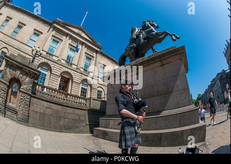 Eine Piper von der Statue des Herzogs von Wellington und der Turm des Balmoral Hotel, Edinburgh, Schottland, Großbritannien Stockfoto