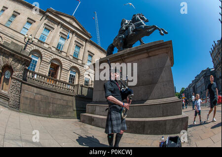 Eine Piper von der Statue des Herzogs von Wellington und der Turm des Balmoral Hotel, Edinburgh, Schottland, Großbritannien Stockfoto