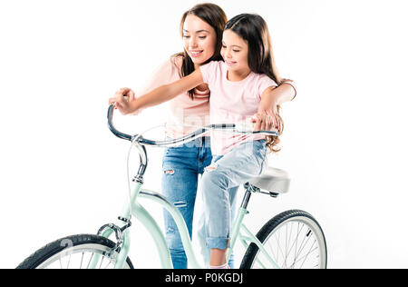 Mutter lehre Vorschüler Tochter mit dem Fahrrad isoliert auf weißem Stockfoto