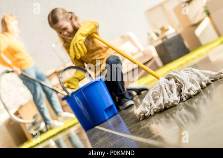 Süße kleine Mädchen mit Wischmopp und Eimer Reinigung neue Wohnung Stockfoto