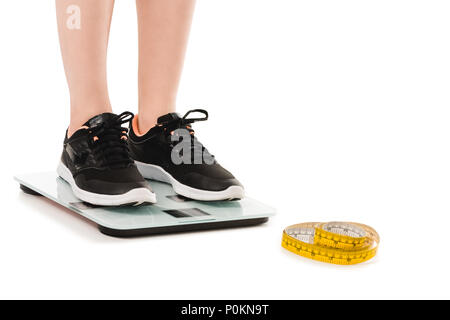 7/8 Schuß von Frau auf Skalen mit Maßband liegend auf dem Boden auf Weiß isoliert Stockfoto