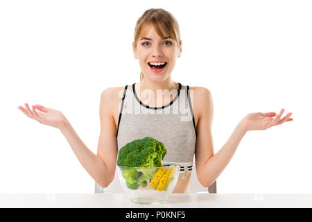 Überrascht junge schlanke Frau mit Broccoli in Maßband in der Schüssel isoliert auf weiss bedeckt Stockfoto