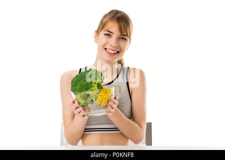 Glücklich, schlanke Frau mit Broccoli in Maßband in der Schüssel isoliert auf weiss bedeckt Stockfoto